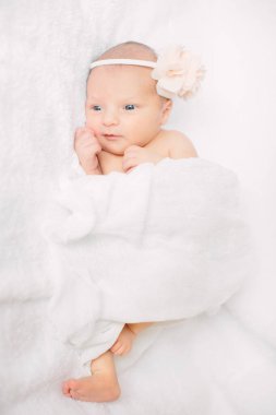 Beyaz saç bandı takmış, kürklü kumaş üzerinde uyuyan yeni doğmuş tatlı bir kız.