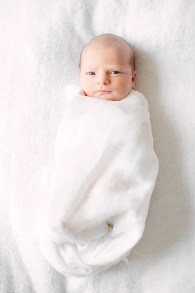 Милая новорожденная девушка спит на пушистой ткани в белой повязке — стоковое фото