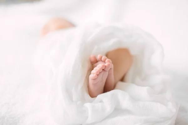 Jambes de bébé nouveau-né sur un tissu à fourrure portant un bandeau blanc — Photo