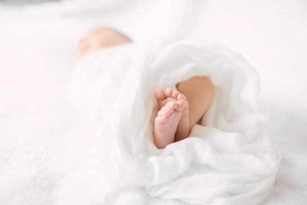 Nyfödda bebis ben på lurvig duk bär vitt pannband — Stockfoto