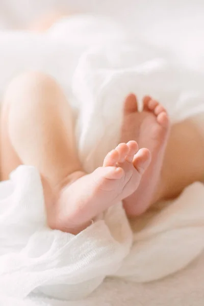 Novorozené dětské nohy na chlupaté látce s bílou čelenkou — Stock fotografie