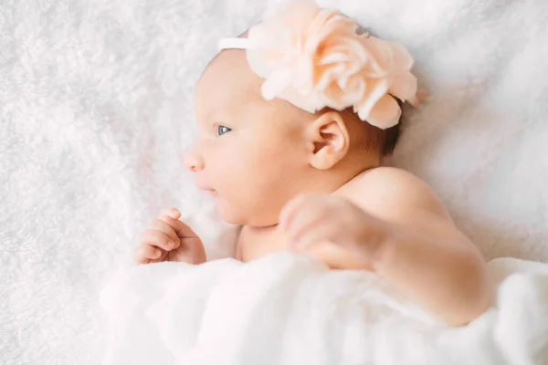 Cute newborn girl sleeping on furry cloth wearing white headband — Stock Photo, Image