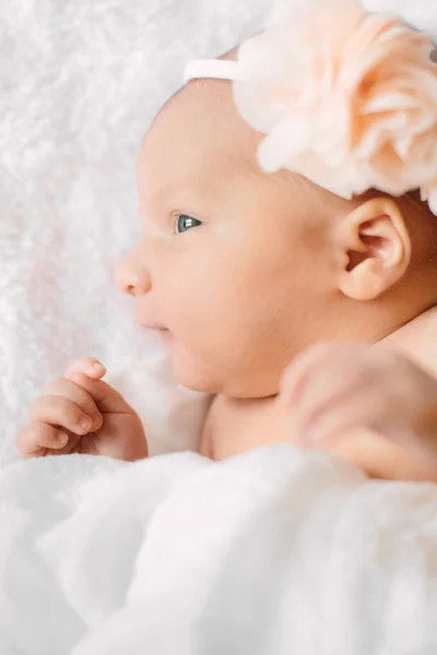 Beyaz saç bandı takmış, kürklü kumaş üzerinde uyuyan yeni doğmuş tatlı bir kız. — Stok fotoğraf
