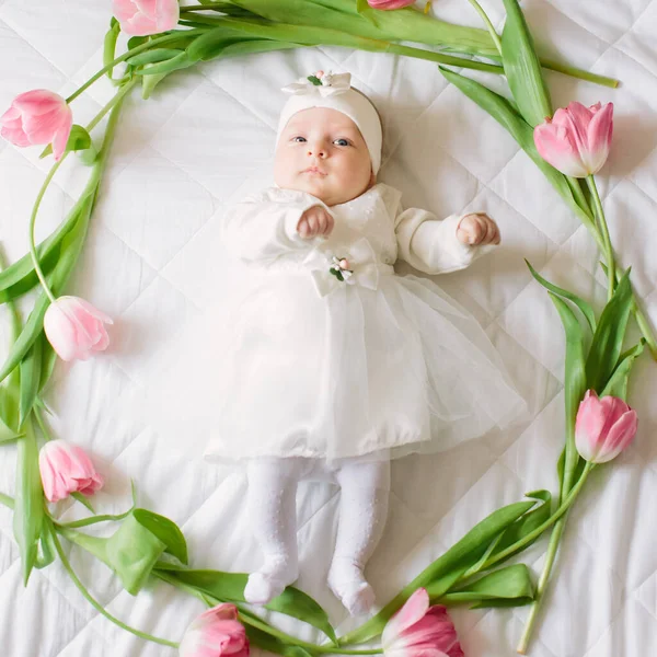 Klein mooi pasgeboren meisje liggend op het bed tussen de bloemen — Stockfoto