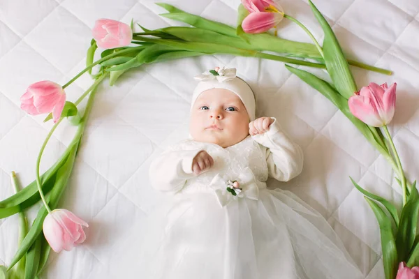 Pequena menina recém-nascida bonita deitada na cama entre as flores — Fotografia de Stock