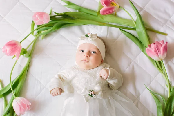 Klein mooi pasgeboren meisje liggend op het bed tussen de bloemen — Stockfoto