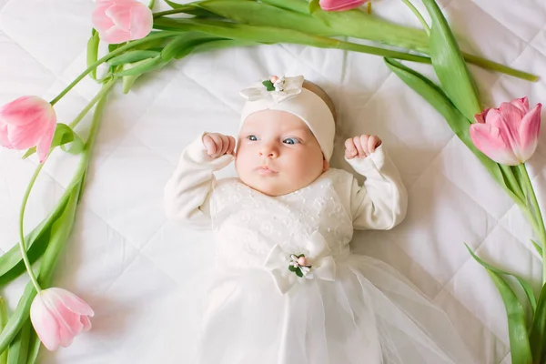 Klein mooi pasgeboren meisje liggend op het bed tussen de bloemen — Stockfoto