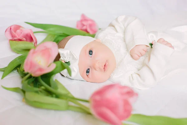 A kis gyönyörű újszülött lány fekszik az ágyon a virágok között. — Stock Fotó