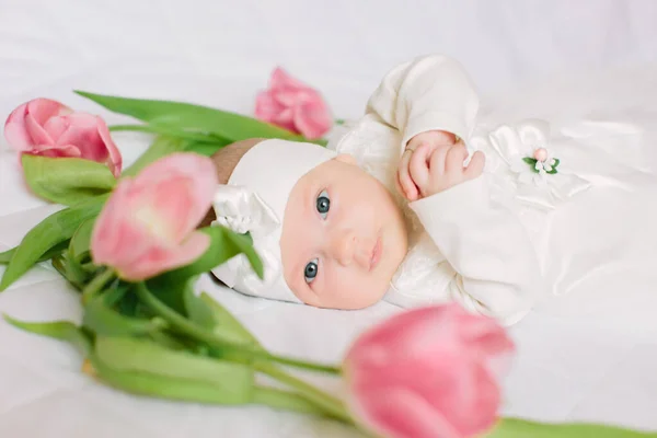 Pequeña niña hermosa recién nacida acostada en la cama entre las flores — Foto de Stock