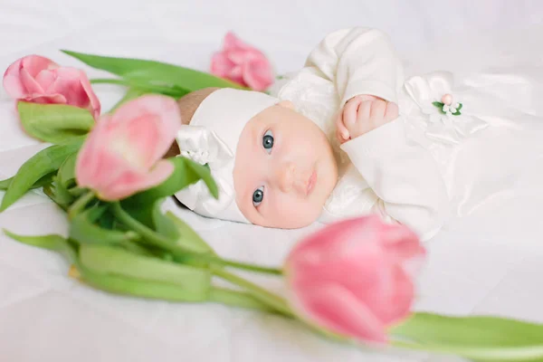 Klein mooi pasgeboren meisje liggend op het bed tussen de bloemen — Stockfoto