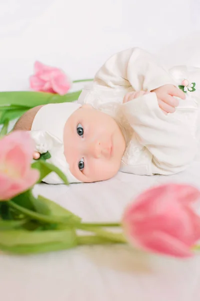 Little beautiful newborn girl lying on the bed among the flowers — Stock Photo, Image