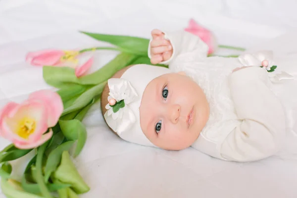 Pequena menina recém-nascida bonita deitada na cama entre as flores — Fotografia de Stock