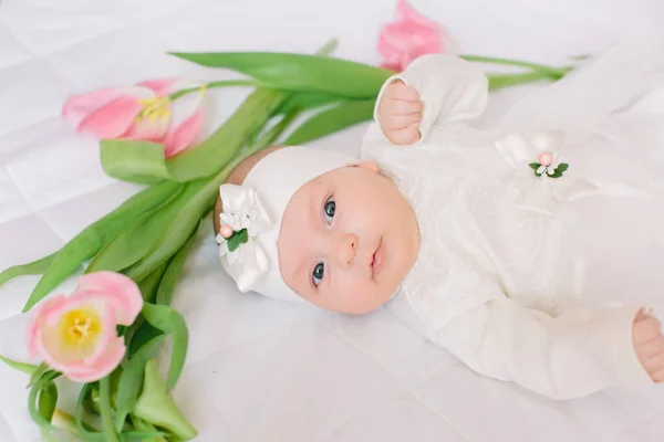 Little beautiful newborn girl lying on the bed among the flowers — Stock Photo, Image