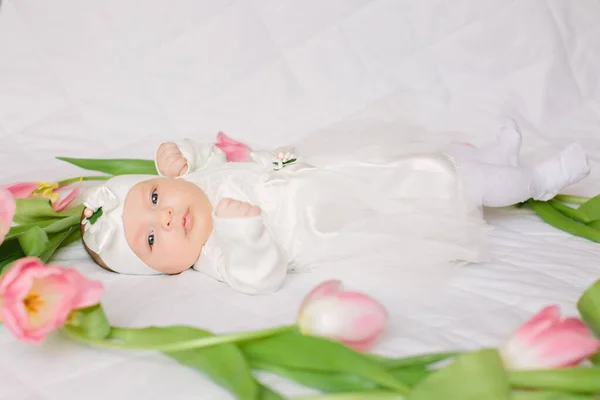 Klein mooi pasgeboren meisje liggend op het bed tussen de bloemen — Stockfoto