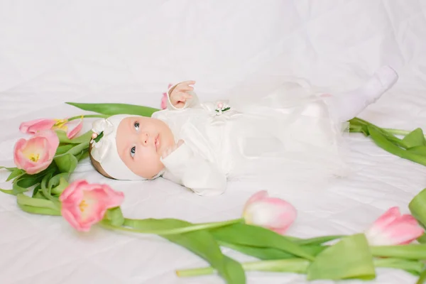 Klein mooi pasgeboren meisje liggend op het bed tussen de bloemen — Stockfoto