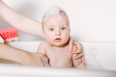 Mutlu gülen Bebek banyo köpük kabarcıkları ile oynarken. Küçük çocuk bir küvet içinde. Bebek yıkama ve banyo. Hijyen ve genç çocuklar için bakım. Yeni doğan bebek banyo