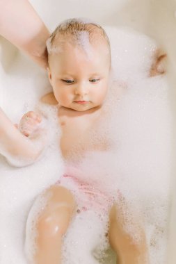 Mutlu gülen Bebek banyo köpük kabarcıkları ile oynarken. Küçük çocuk bir küvet içinde. Bebek yıkama ve banyo. Hijyen ve genç çocuklar için bakım. Çok güzel banyo bebek sabun köpük saç ile