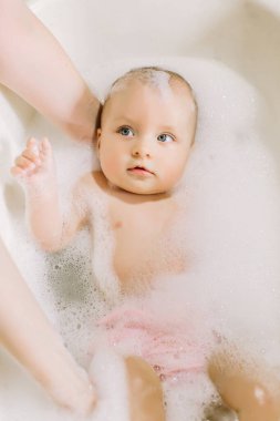 Mutlu gülen Bebek banyo köpük kabarcıkları ile oynarken. Küçük çocuk bir küvet içinde. Bebek yıkama ve banyo. Hijyen ve genç çocuklar için bakım. Çok güzel banyo bebek sabun köpük saç ile