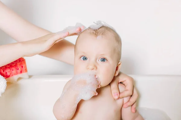 Feliz bebê rindo tomando um banho brincando com bolhas de espuma. Criança em uma banheira. Lavagem infantil e banho. Higiene e cuidados para crianças pequenas . — Fotografia de Stock