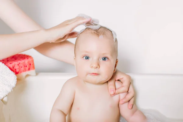 Feliz bebê rindo tomando um banho brincando com bolhas de espuma. Criança em uma banheira. Lavagem infantil e banho. Higiene e cuidados para crianças pequenas . — Fotografia de Stock