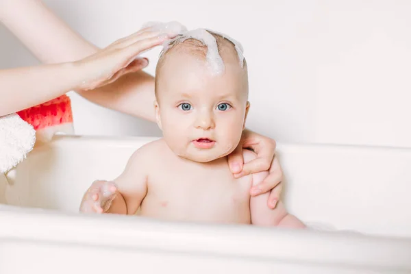 Glücklich lachendes Baby, das ein Bad nimmt und mit Schaumblasen spielt. Kind in der Badewanne. Säuglingswäsche und Baden. Hygiene und Betreuung von Kleinkindern. — Stockfoto