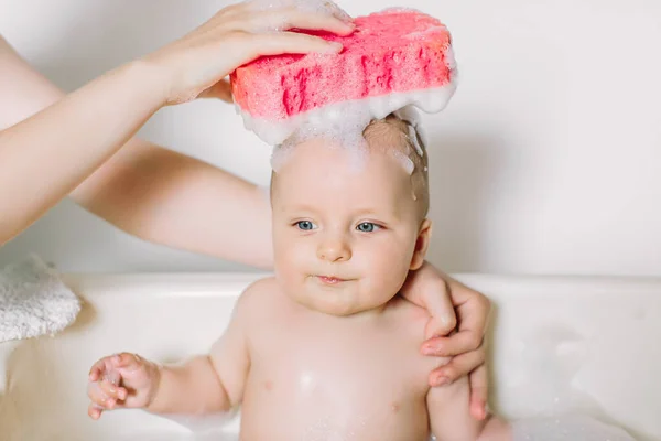 Feliz bebê rindo tomando um banho brincando com bolhas de espuma. Criança em uma banheira. Lavagem infantil e banho. Higiene e cuidados para crianças pequenas. Banho de recém-nascido — Fotografia de Stock