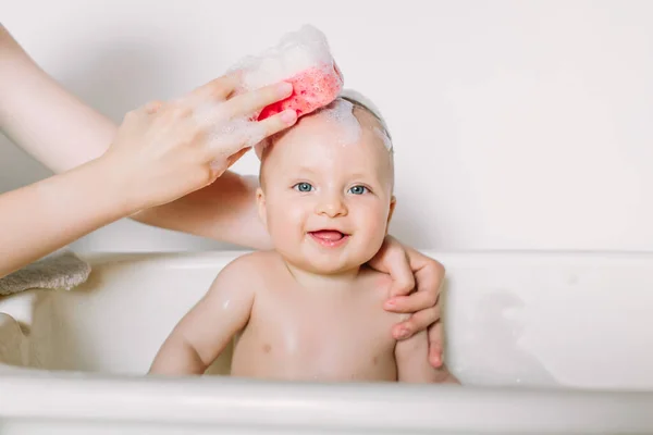 Buon bambino ridente che fa il bagno giocando con le bolle di schiuma. Bambino piccolo in una vasca da bagno. Lavaggio e bagno dei neonati. Igiene e cura dei bambini piccoli. Neonato bagnato — Foto Stock