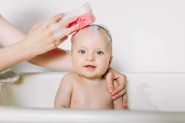 Feliz bebê rindo tomando um banho brincando com bolhas de espuma. Criança em uma banheira. Lavagem infantil e banho. Higiene e cuidados para crianças pequenas. Banho de recém-nascido — Fotografia de Stock