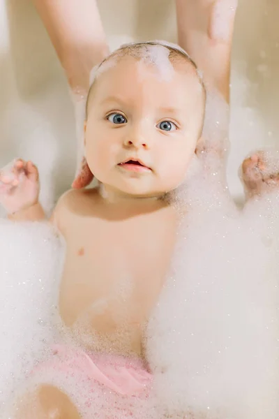 Boldog nevető baba játszik bubbles hab fürödtem. Kis gyermek a fürdőkádban. Mosás csecsemő- és fürdő. Higiéniai és kisgyermekek gondozása. Újszülött baba fürdés — Stock Fotó