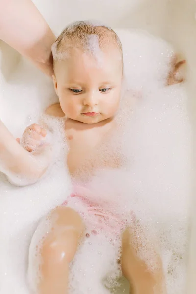 Feliz bebê rindo tomando um banho brincando com bolhas de espuma. Criança em uma banheira. Lavagem infantil e banho. Higiene e cuidados para crianças pequenas. Adorável bebê banho com sabão suds no cabelo — Fotografia de Stock