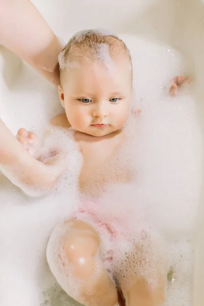 Buon bambino ridente che fa il bagno giocando con le bolle di schiuma. Bambino piccolo in una vasca da bagno. Lavaggio e bagno dei neonati. Igiene e cura dei bambini piccoli. Adorabile bambino da bagno con sapone sui capelli — Foto Stock