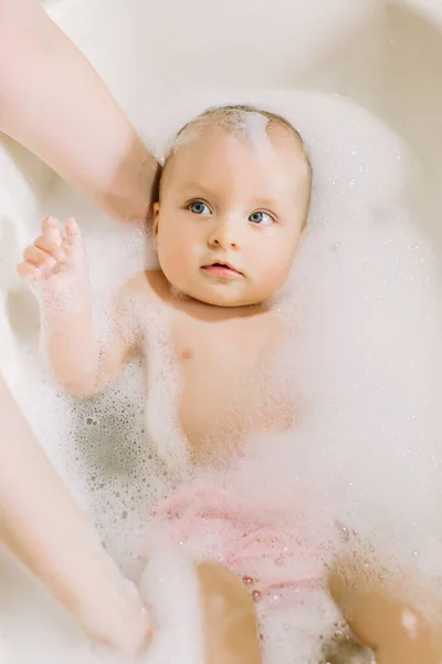 Щаслива смішна дитина приймає ванну, граючи з бульбашками піни. Маленька дитина у ванній. Миття та купання немовлят. Гігієна та догляд за маленькими дітьми. Чарівна дитина для ванни з милом раптом на волоссі — стокове фото