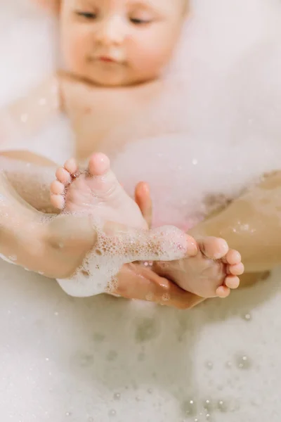 Glücklich lachendes Baby, das ein Bad nimmt und mit Schaumblasen spielt. Kind in der Badewanne. Säuglingswäsche und Baden. Hygiene und Betreuung von Kleinkindern. entzückendes Badebaby mit Seifenlauge auf den Haaren — Stockfoto