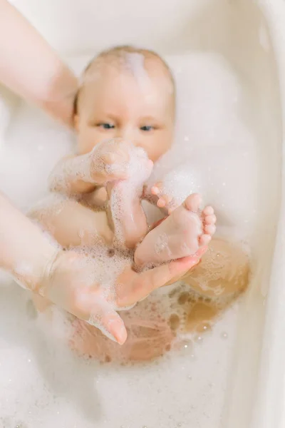 Bebê pequeno feliz uma natação na banheira.Retrato de banho de bebê em uma banheira com espuma — Fotografia de Stock