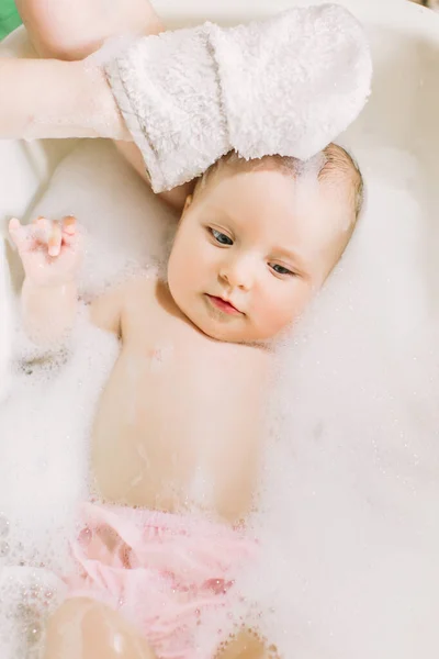 Buon bambino ridente che fa il bagno giocando con le bolle di schiuma. Bambino piccolo in una vasca da bagno. Lavaggio e bagno dei neonati. Igiene e cura dei bambini piccoli. Adorabile bambino da bagno con sapone sui capelli — Foto Stock