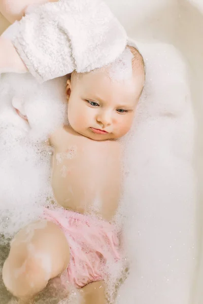 Glücklich lachendes Baby, das ein Bad nimmt und mit Schaumblasen spielt. Kind in der Badewanne. Säuglingswäsche und Baden. Hygiene und Betreuung von Kleinkindern. entzückendes Badebaby mit Seifenlauge auf den Haaren — Stockfoto