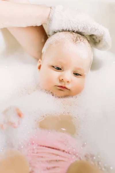 Bebê pequeno feliz uma natação na banheira.Retrato de banho de bebê em uma banheira com espuma — Fotografia de Stock