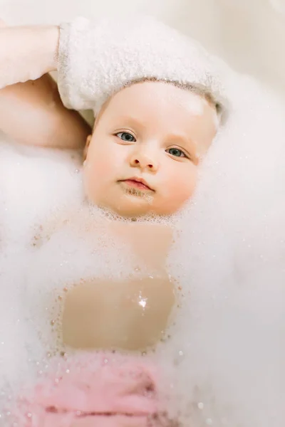 Boldog kis babaúszás a fürdőszobában. Baba fürdés a fürdő hab portréja — Stock Fotó