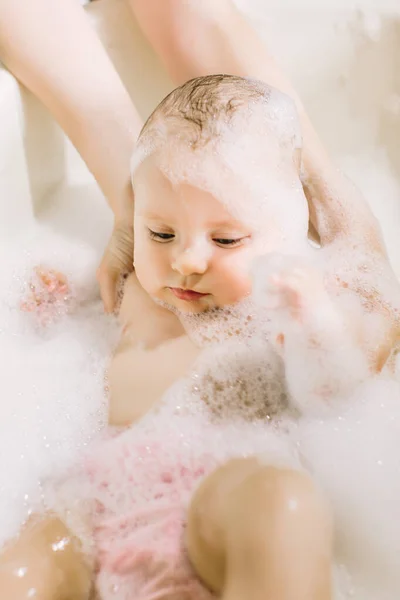 Bebê pequeno feliz uma natação na banheira.Retrato de banho de bebê em uma banheira com espuma — Fotografia de Stock