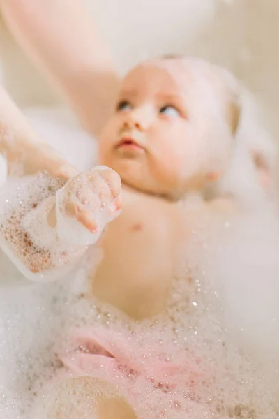 Feliz bebê rindo tomando um banho brincando com bolhas de espuma. Criança em uma banheira. Lavagem e banhos infantis . — Fotografia de Stock