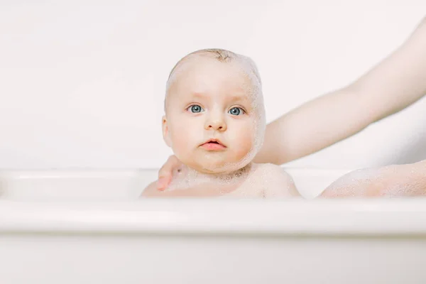 Feliz bebê rindo tomando um banho brincando com bolhas de espuma. Criança em uma banheira. Lavagem e banhos infantis . — Fotografia de Stock