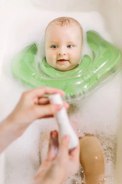 Baby nuoto con anello nuoto collo verde. mamma spreme shampoo dal tubo — Foto Stock
