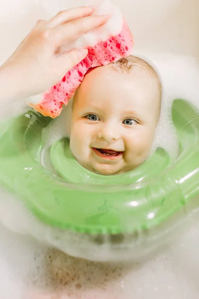 Babaúszás zöld nyak úszni gyűrűvel. Anya baba fej vörös szivacs mosás — Stock Fotó