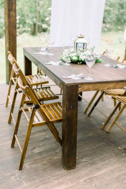 Ormanda düğün yemeği masası dekorasyonu. Düğün ya da yemek resepsiyonu için ahşap masa kurulumu. Masada taşralı dekorasyonlar var.