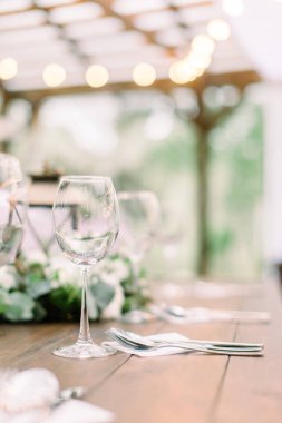 Çiçek süslemeleri ve fenerlerle dolu köy sofrası. Şarap kadehleri masada. Açık havada bir restoranda düğün veya yemek masası.