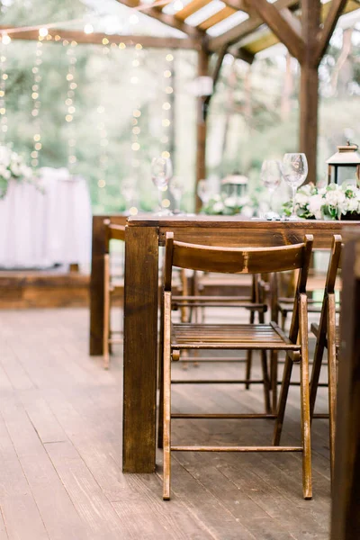 Cenário de mesa vintage com decorações florais, flores brancas, vegetação e lanternas em um piso de madeira em restaurante ao ar livre em jardim ou floresta — Fotografia de Stock