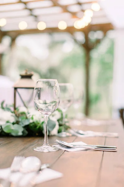 Definição de mesa rústica com decorações florais, lanternas. Vinhos em cima da mesa. Mesa de casamento ou jantar no restaurante ao ar livre — Fotografia de Stock