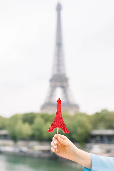 Weibliche Hand mit rotem Eiffelturmlutscher vor dem Eiffelturm in Paris an einem sonnigen Tag — Stockfoto