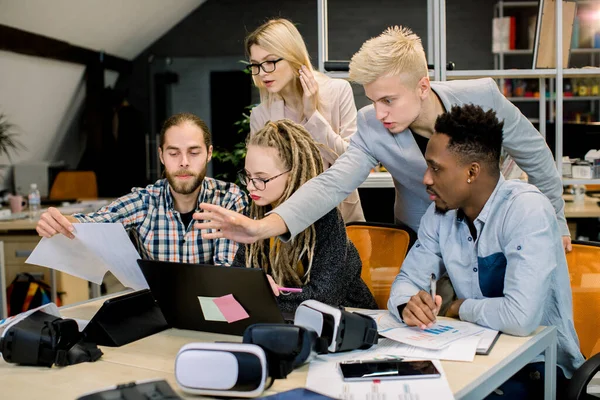 Gruppe von fünf multiethnischen Geschäftsleuten in Freizeitkleidung arbeiten und Brainstorming zusammen im modernen Büro, mit Laptop, Vr-Brille. Unternehmenskonzept People — Stockfoto