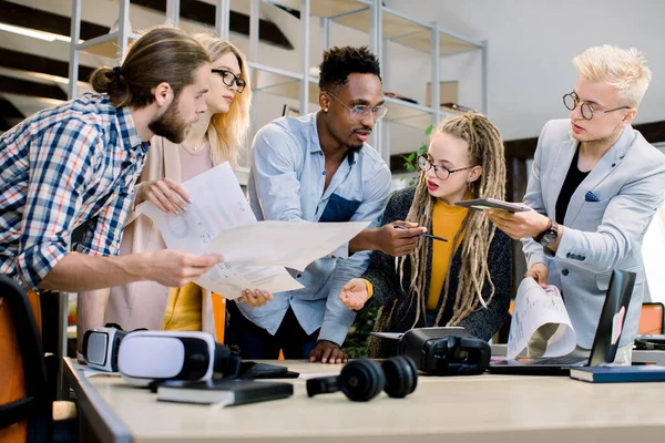 Ett team av unga multietniska affärsmän i vardagskläder arbetar och kommunicerar tillsammans på ett kontor. Företag affärsånga dela sina idéer för nya stora start — Stockfoto